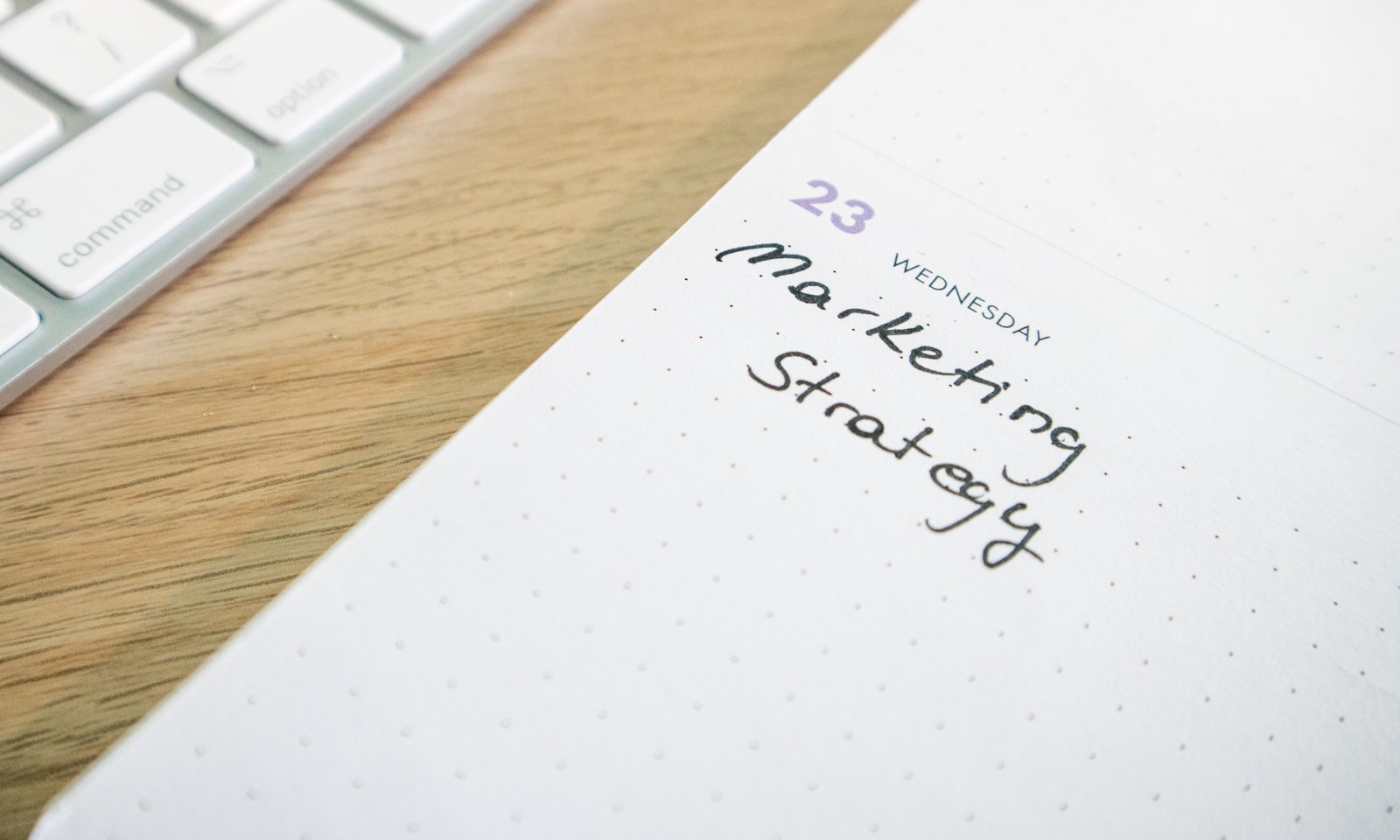 Open planner notebook with "Marketing Strategy" written across the page, beside a keyboard on a clean desk